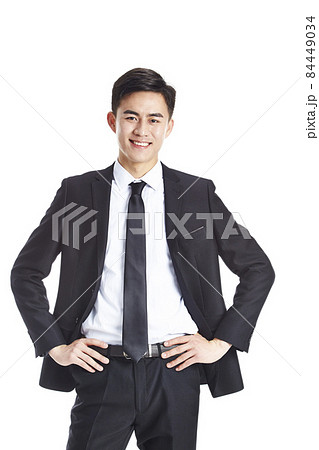 studio portrait of young asian business man arms akimbo looking at camera smiling isolated on white 84449034
