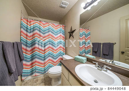 Bathroom interior with vanity sink and colorful zigzag patterned shower curtain 84449048