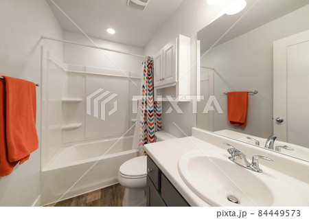 White bathroom with wall cabinet and colorful shower curtain 84449573