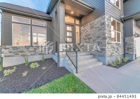 Two storey home facade with stone brick wall and glass paned gray front door Two storey home facade with stone brick wall and glass paned gray front door 84451493