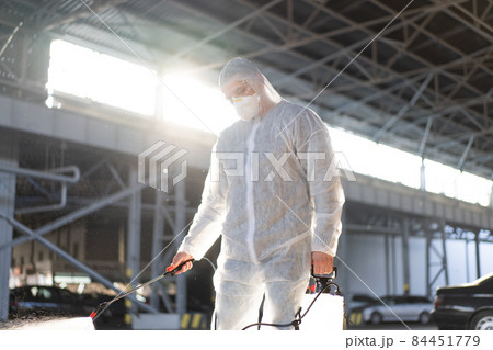 Man dressed white protective overalls spraying surface antibacterial sanitizer sprayer during quarantine Man dressed white protective overalls spraying surface antibacterial sanitizer sprayer during quarantine 84451779