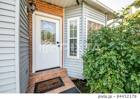 Front door exterior with bricks and vinyl siding wall 84452179