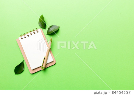 eco-friendly Empty notebook with pen and green leaf on Colored background for note eco-friendly Empty notebook with pen and green leaf on Colored background for note 84454557