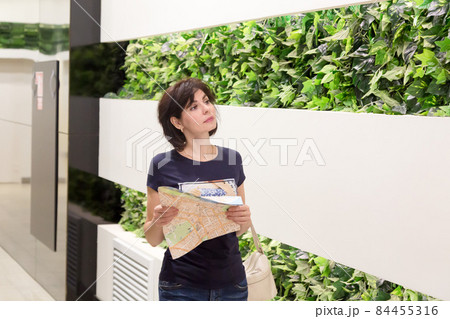 A customer with a drawing in her hands is looking for the right store in a huge shopping center A customer with a drawing in her hands is looking for the right store in a huge shopping center 84455316