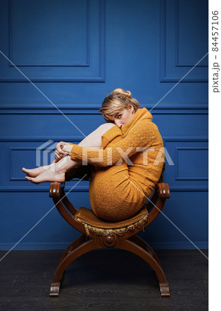 Young woman curled up in an old armchair 84457106