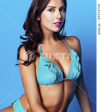 young pretty brunette girl in bikini smiling studio blue background, lifestyle people concept 84459709