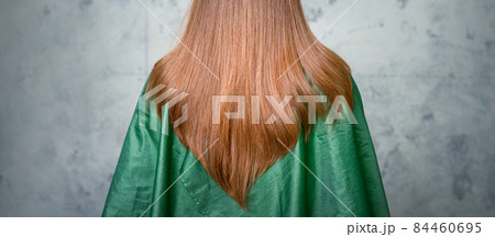 Rear View of a woman with long brown hair against a gray background. 84460695