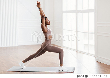 Young black woman standing in warrior pose on fitness mat 84461063