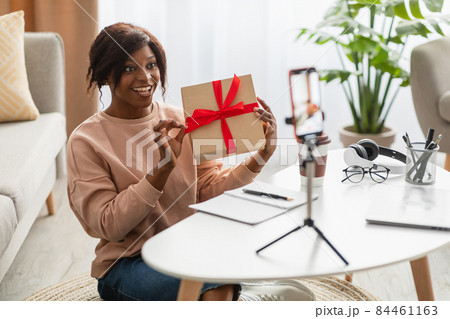 African Female Showing Wrapped Gift To Cellphone Making Video Indoor African Female Showing Wrapped Gift To Cellphone Making Video Indoor 84461163
