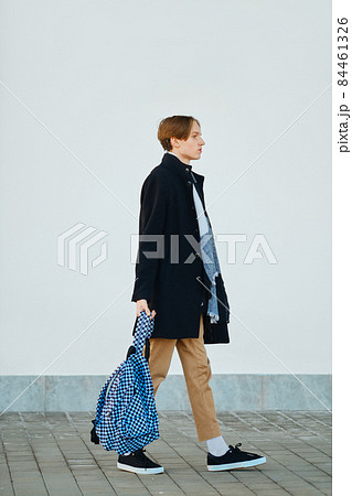 Full length shot of young student walks with backpack in old wool coat, scarf and short trousers outdoor Full length shot of young student walks with backpack in old wool coat, scarf and short trousers outdoor 84461326