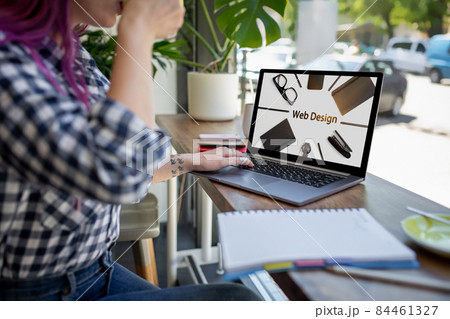 Cropped shot view of young woman working on laptop computer while sitting in modern cafe bar interior. Design. Web design 84461327