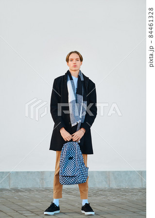 Full length shot of young student holds backpack in old wool coat, scarf and short trousers outdoor 84461328