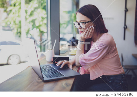 Side view of young businesswoman sitting at table in coffee shop 84461396