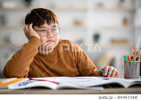 Asian schooler chubby boy dreaming about something while doing homework Asian schooler chubby boy dreaming about something while doing homework 84461566