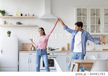 Happy cheerful millennial husbands lady dancing, have fun together in kitchen interior Happy cheerful millennial husbands lady dancing, have fun together in kitchen interior 84461765