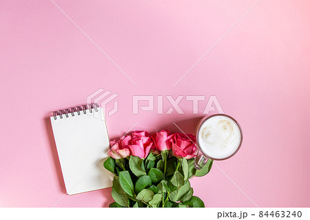 The cup of hot coffee, empty notepad with funny pen and bouquet of fresh roses on soft pink background. The cup of hot coffee, empty notepad with funny pen and bouquet of fresh roses on soft pink background. 84463240