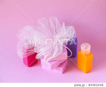 Colorful washcloth, plastic travel bottles and bars of soap on a soft pink background. Accessories for body care and hygiene. Colorful washcloth, plastic travel bottles and bars of soap on a soft pink background. Accessories for body care and hygiene. 84463448