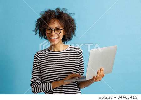 Cheerful young woman using laptop in studio Cheerful young woman using laptop in studio 84465415