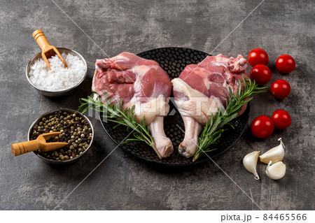 Two raw duck legs and fresh rosemary on a black plate. Two raw duck legs and fresh rosemary on a black plate. 84465566