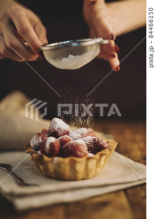 woman dusting sugar powder strawberry tart. High quality photo 84466150