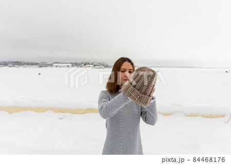 Portrait of young elegant brunette girl in dress on background winter road with warm hat 84468176