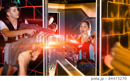 Laser tag players guys and girls playing in teams in dark laser Laser tag players guys and girls playing in teams in dark laser 84473270