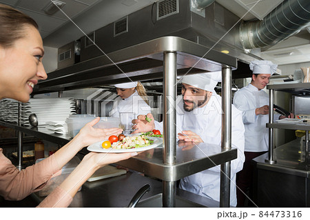 Head chef checking dishes in kitchen Head chef checking dishes in kitchen 84473316