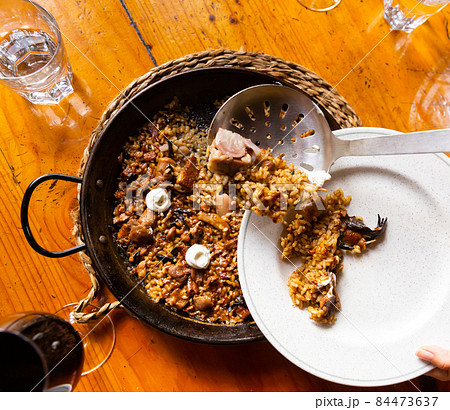 Customer putting paella from pan to plate 84473637