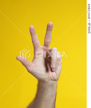 Male hand gesture on yellow background. Man hand isolated showing three fingers. Male hand gesture on yellow background. Man hand isolated showing three fingers. 84473804