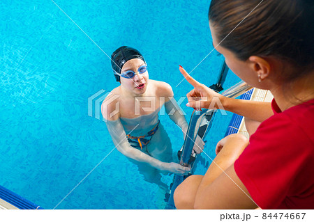 Female Coach In Water Giving preteen boy swimming Lesson In Indoor Pool Female Coach In Water Giving preteen boy swimming Lesson In Indoor Pool 84474667