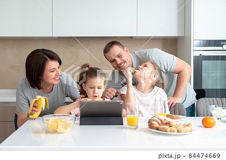 Smiling Family Dining Together at kitchen table and having fun, parents with two daughters Smiling Family Dining Together at kitchen table and having fun, parents with two daughters 84474669