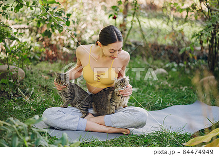 Girl sitting in a summer park with cute cat 84474949