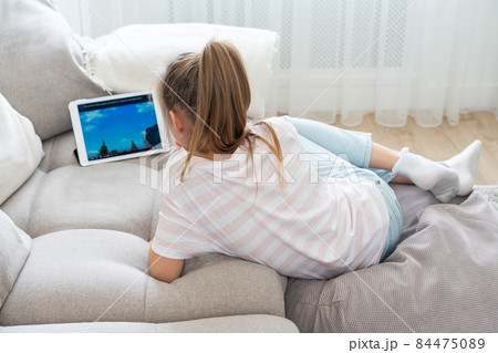 Girl Lying On Couch And Using Tablet 84475089