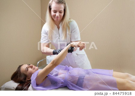 Waxing in beauty salon by professional. Beauty salon worker applying wax and tape to remove hair from arms Waxing in beauty salon by professional. Beauty salon worker applying wax and tape to remove hair from arms 84475918