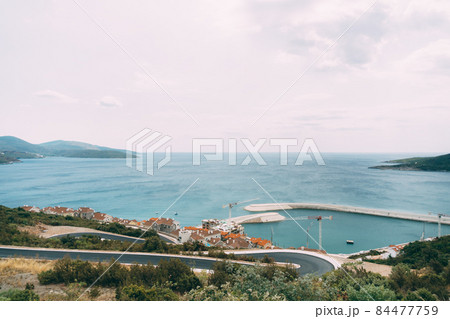View from the mountains to the Lustica bay, pier and buildings. Montenegro View from the mountains to the Lustica bay, pier and buildings. Montenegro 84477759