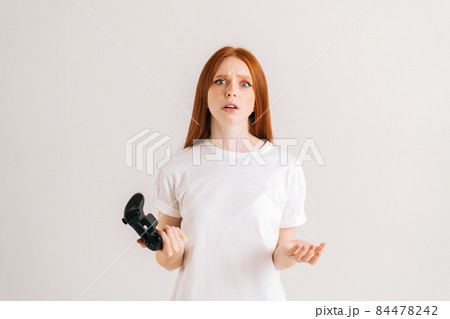 Studio portrait of frustrated pretty young woman losing at video games on console with controller on white isolated background. Studio portrait of frustrated pretty young woman losing at video games on console with controller on white isolated background. 84478242