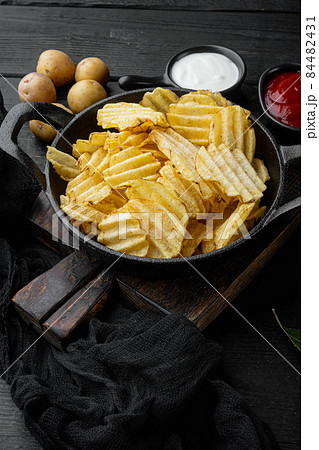 Crispy potato chips, on black wooden background Crispy potato chips, on black wooden background 84482431