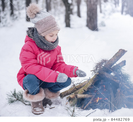 Little girl in a bright jacket plays in the winter forest 84482769