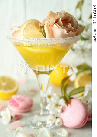 Glass of cocktail, ingredients and flowers against wooden background 84483334