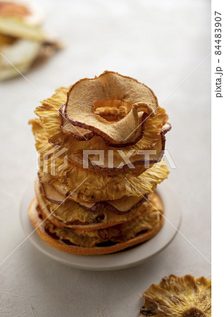 Dried fruits. Stack of pineapple and apples slices on bright background. Vegan, healthy snack or dessert Dried fruits. Stack of pineapple and apples slices on bright background. Vegan, healthy snack or dessert 84483907