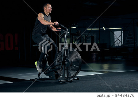 Male using air bike for cardio workout at cross training gym. 84484376