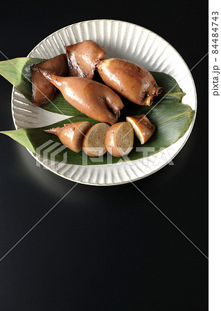 笹の葉に乗っている郷土料理のイカ飯を黒背景で俯瞰撮影 84484743