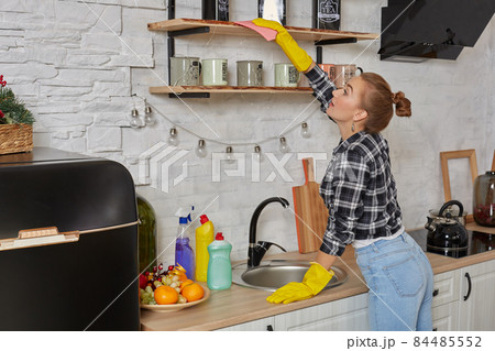Woman in gloves cleaning furniture with rag at home kitchen. 84485552