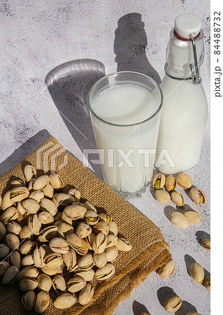 Glass of healthy pistachio milk stands on concrete background. Diet milk, vegetarian food. Gluten free. Close-up. Pistachio lactose free milk for dietary nutrition. Alternative food and vegetarianism. Glass of healthy pistachio milk stands on concrete background. Diet milk, vegetarian food. Gluten free. Close-up. Pistachio lactose free milk for dietary nutrition. Alternative food and vegetarianism. 84488732