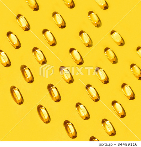 Yellow oval pills capsules vitamin Omega 3 over yellow 84489116