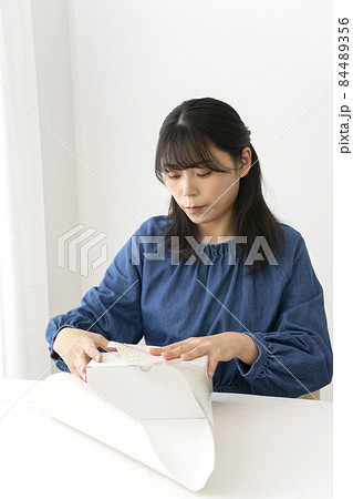 リビングのテーブルで贈り物を包装紙で包む女性 リビングのテーブルで贈り物を包装紙で包む女性 84489356