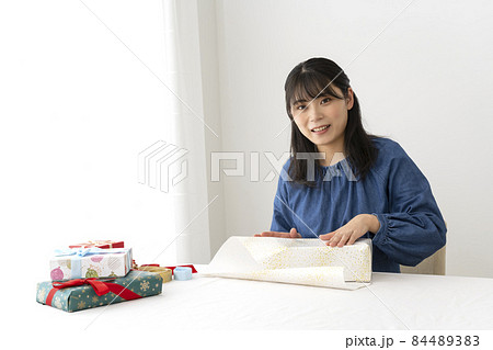リビングのテーブルで贈り物を包装紙で包む女性 リビングのテーブルで贈り物を包装紙で包む女性 84489383