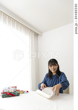 リビングのテーブルで贈り物を包装紙で包む女性 リビングのテーブルで贈り物を包装紙で包む女性 84489390
