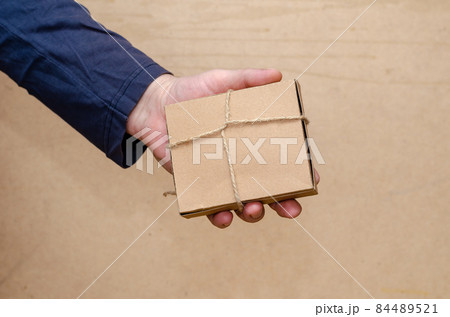 An adult male is holding a brown gift box in his hand. The recta An adult male is holding a brown gift box in his hand. The recta 84489521