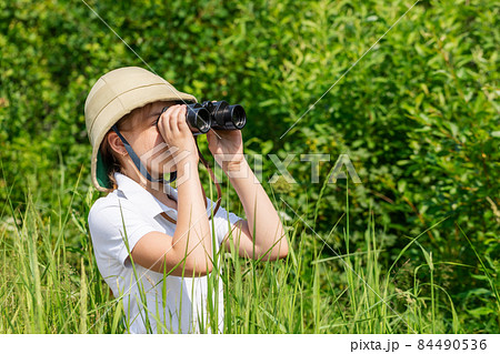Young explorer looking through binoculars outdoors Young explorer looking through binoculars outdoors 84490536